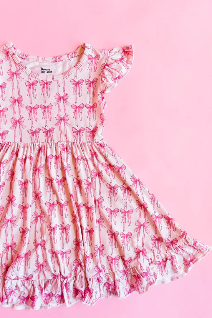 A pink and white ruffle dress with a bow pattern.