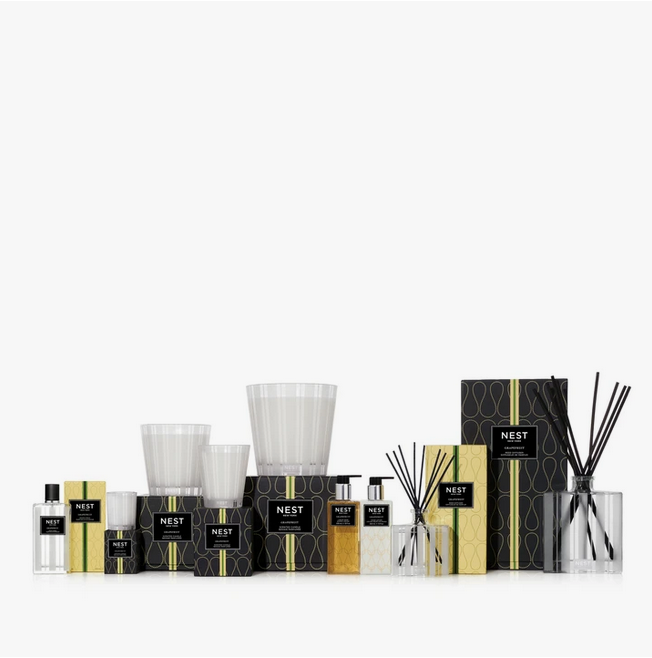 A collection of Nest New York home fragrance products in black and gold packaging.