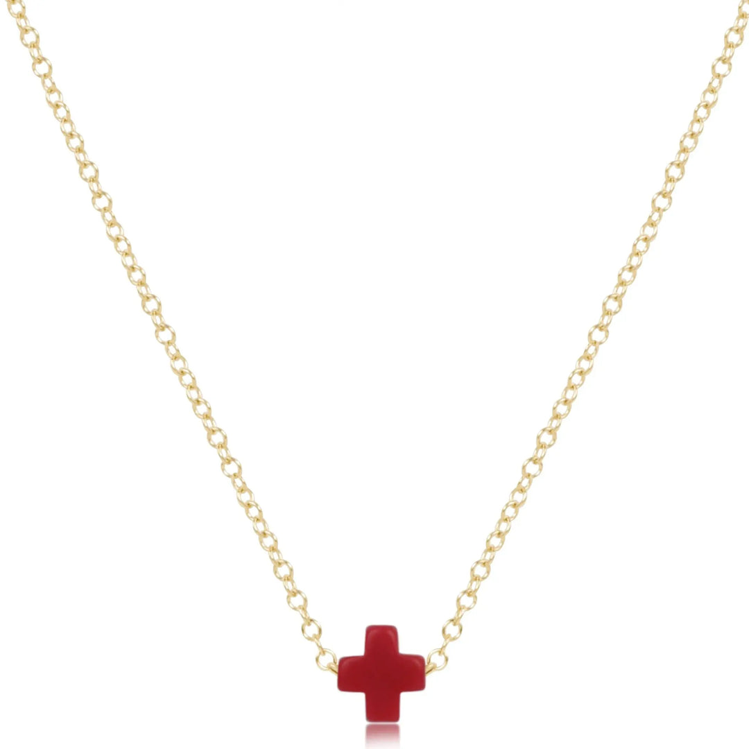 A gold chain necklace with a small red cross pendant.