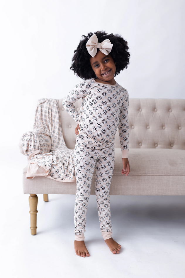 A young girl in a Sandy Smiles Checker Dream Set stands next to a beige couch.