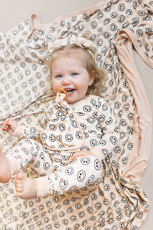 A smiling toddler wears a Sandy Smiles Checker Dream Set and matching bow.