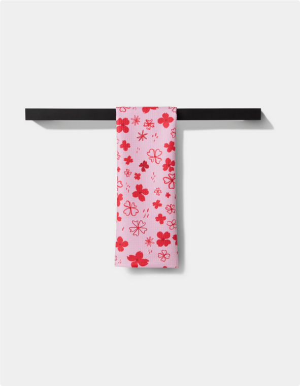 Pink tea towel with red dogwood hearts and floral patterns.