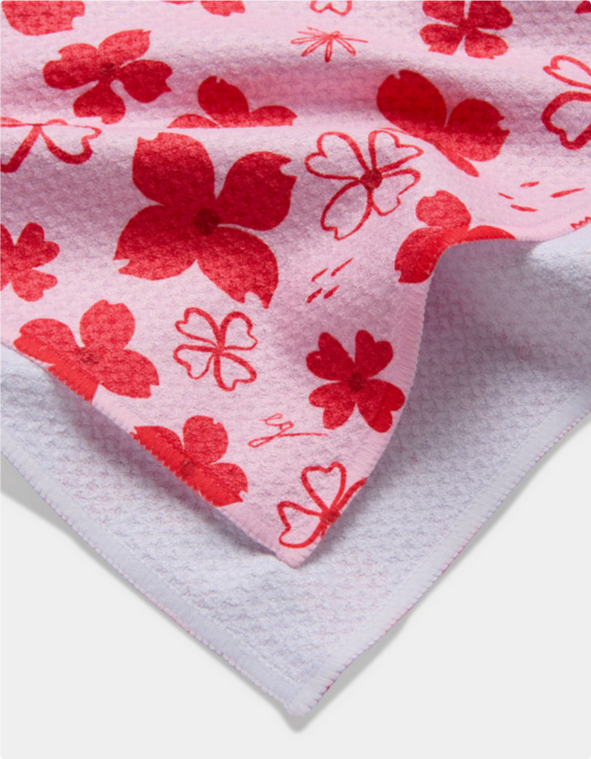 Pink tea towel with red dogwood flower and heart patterns.
