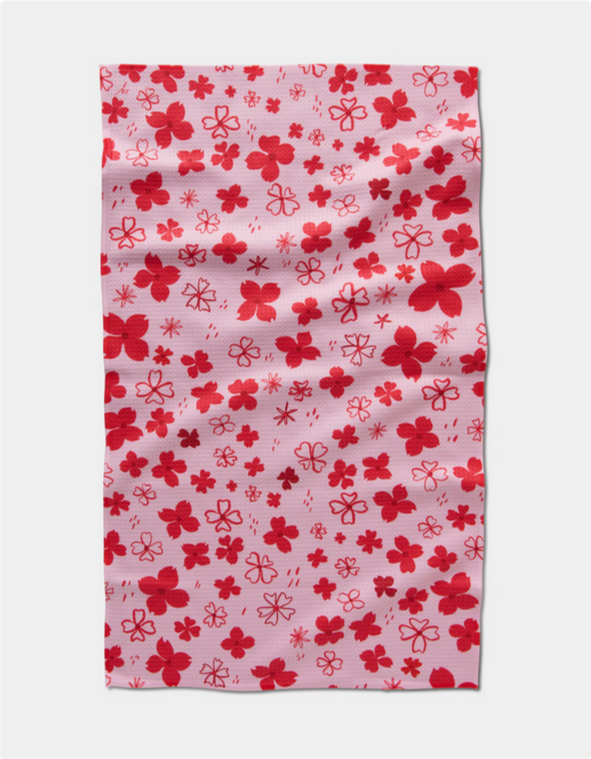 Pink tea towel with a pattern of red dogwood hearts.