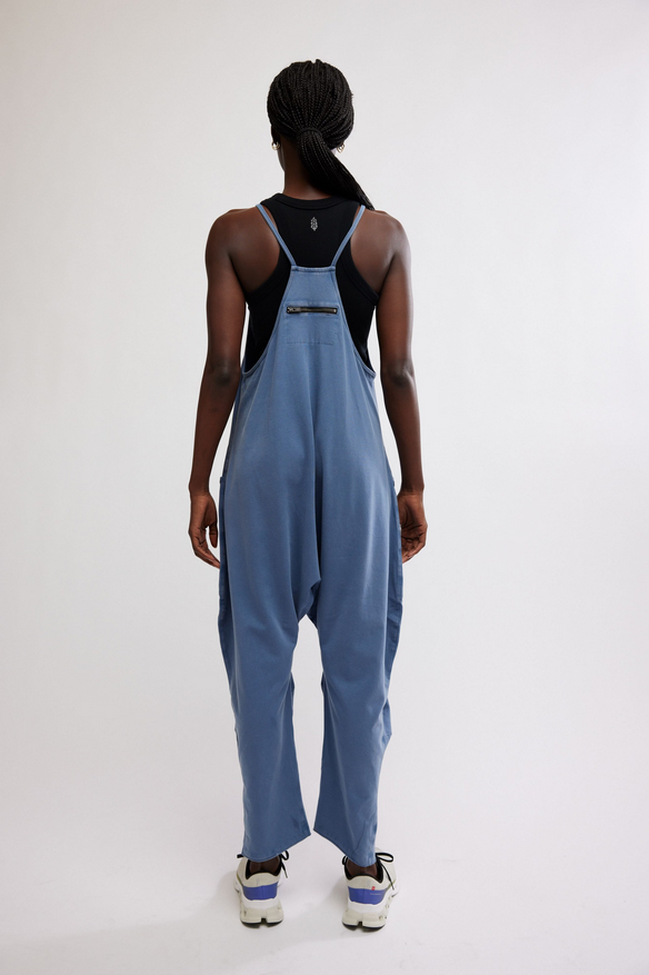 A person from behind wears a blue onesie with a black tank top and white sneakers.