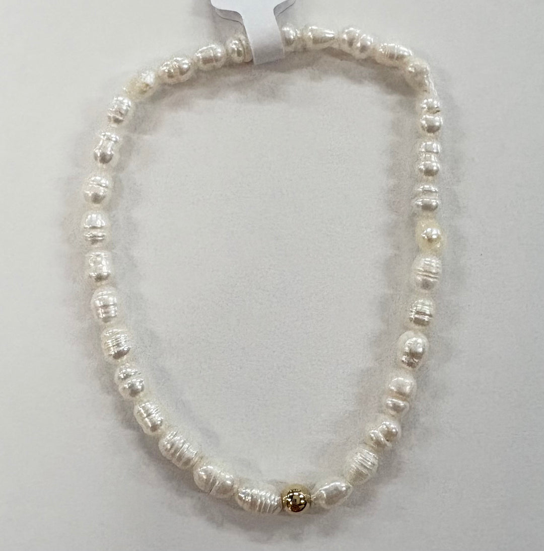 Glass bead bracelet with white beads and a single gold bead.