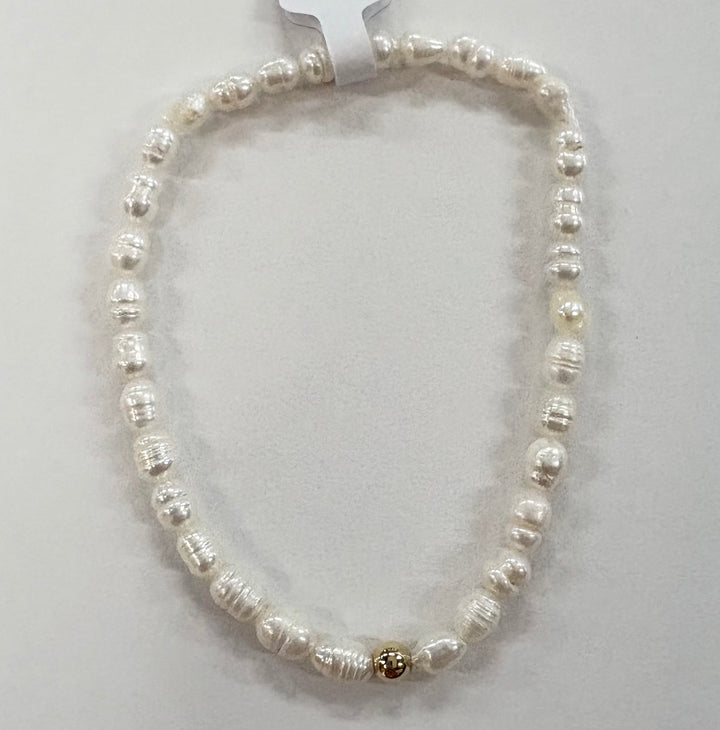 Glass bead bracelet with white beads and a single gold bead.