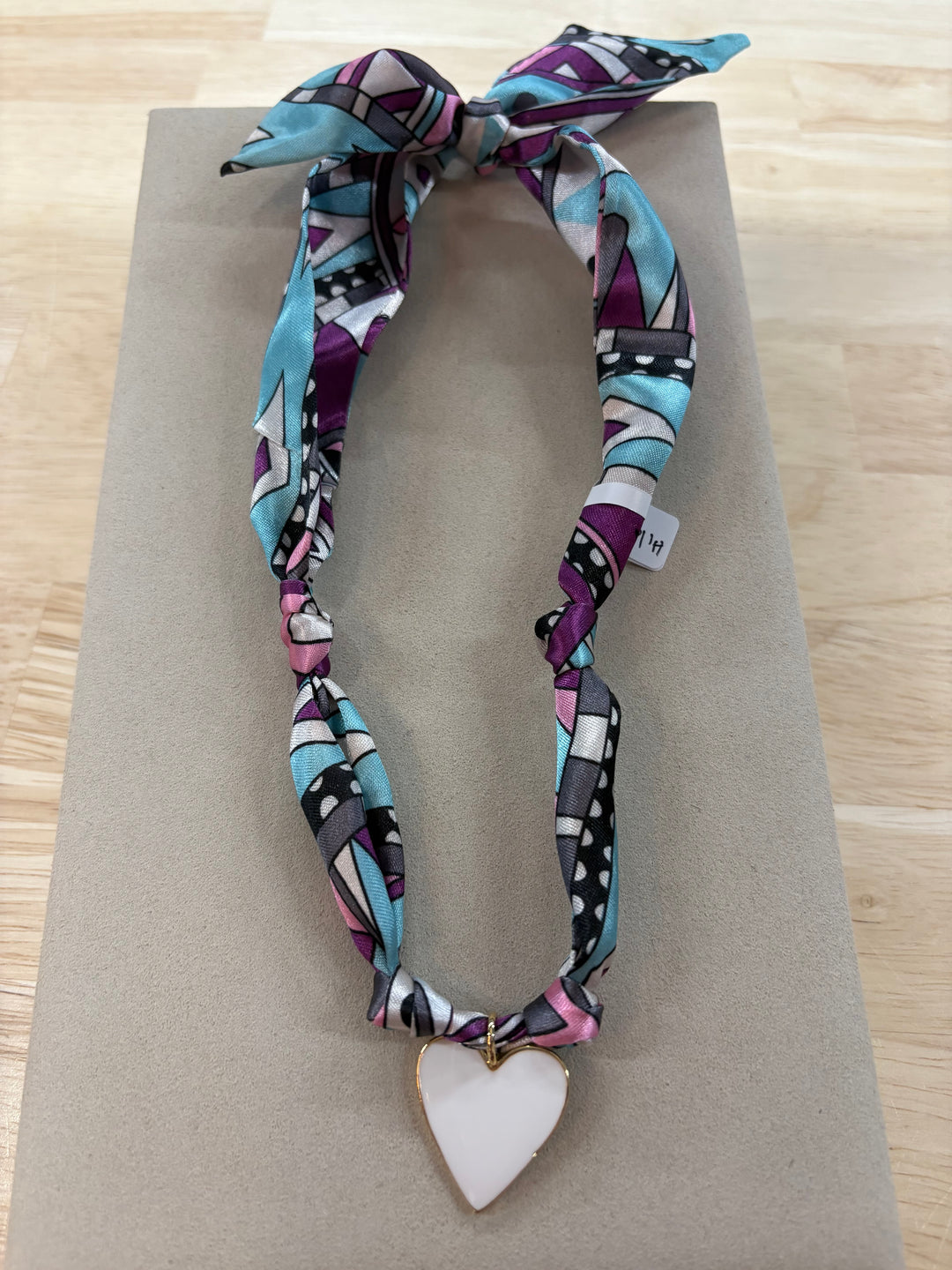 A Hilary satin scarf necklace with a white heart charm.
