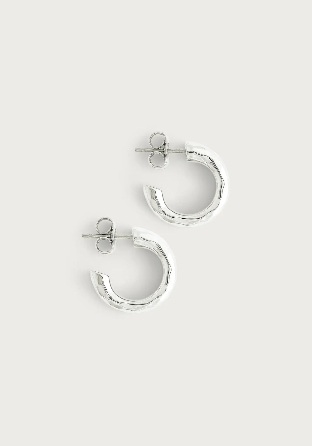 Silver huggie hoop earrings with a hammered texture.