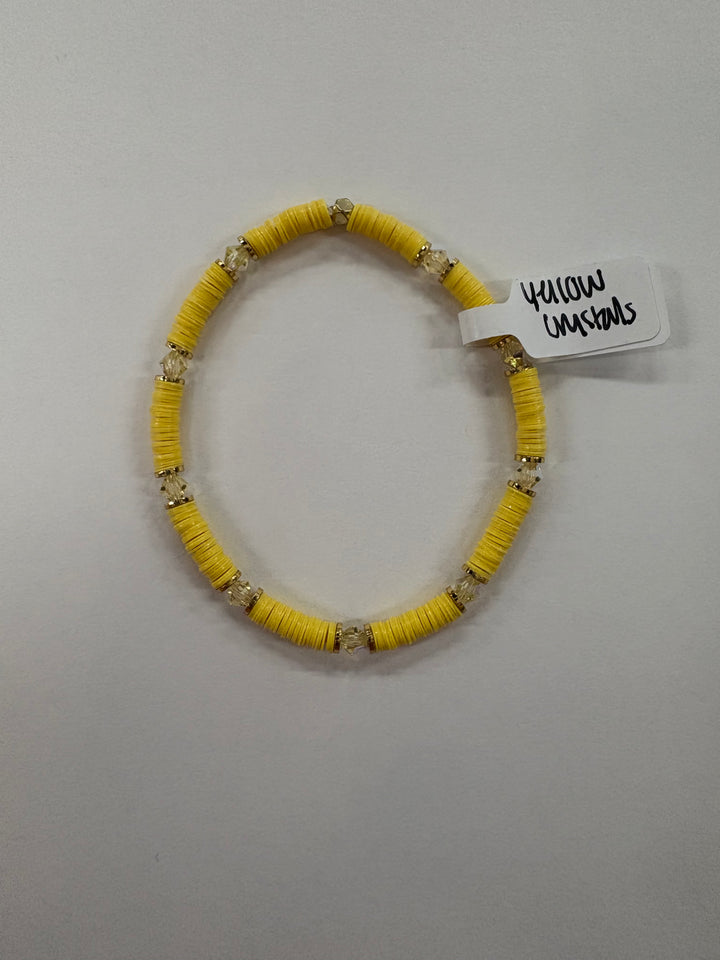 A yellow flat bead bracelet with clear crystal accents and a tag reading "Yellow Crystals."