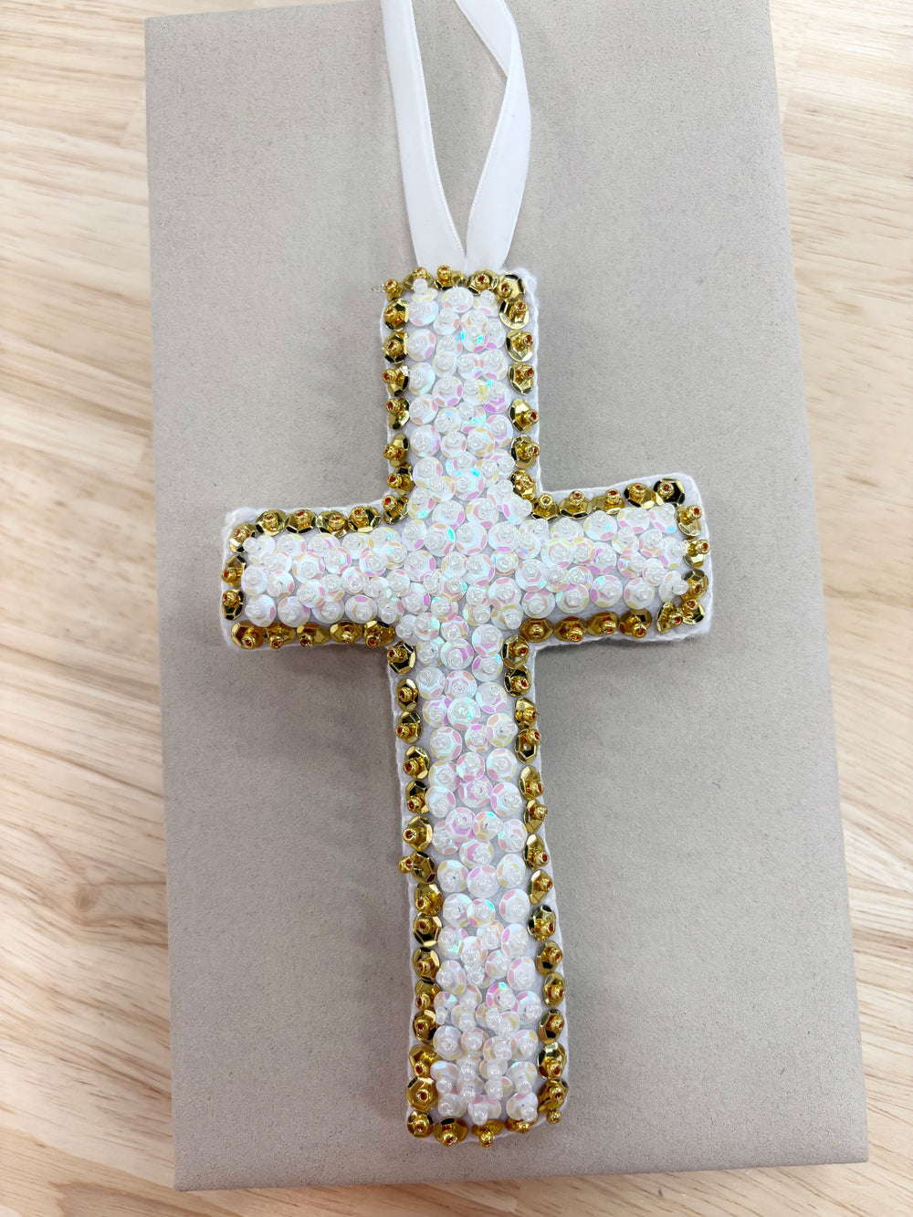 Large white and gold hand-beaded cross ornament with a white ribbon.
