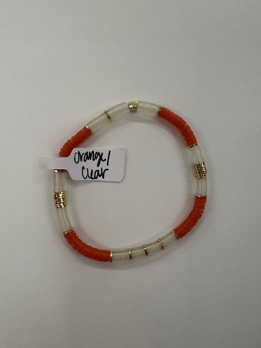 A small flat bead bracelet with orange and clear beads and gold accents.