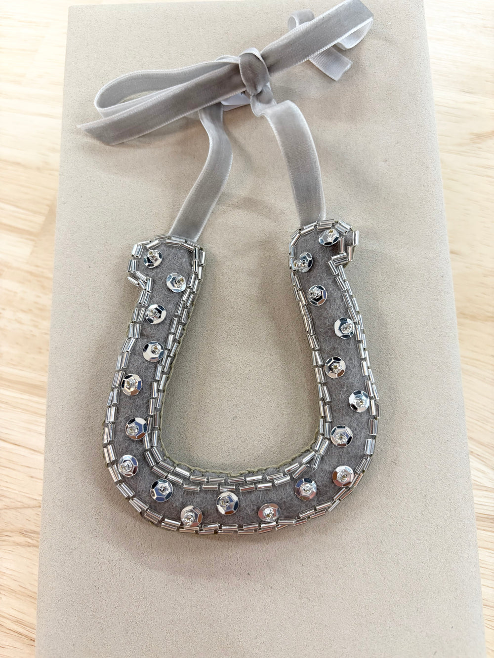 Hand-beaded horseshoe ornament with a gray velvet ribbon.