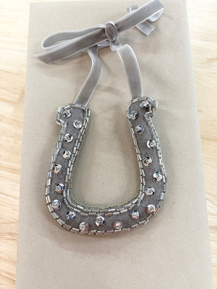 Hand-beaded horseshoe ornament with a gray velvet ribbon.
