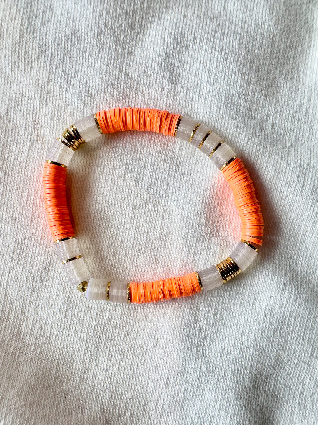Large flat bead bracelet with orange and clear vinyl beads and gold accents.
