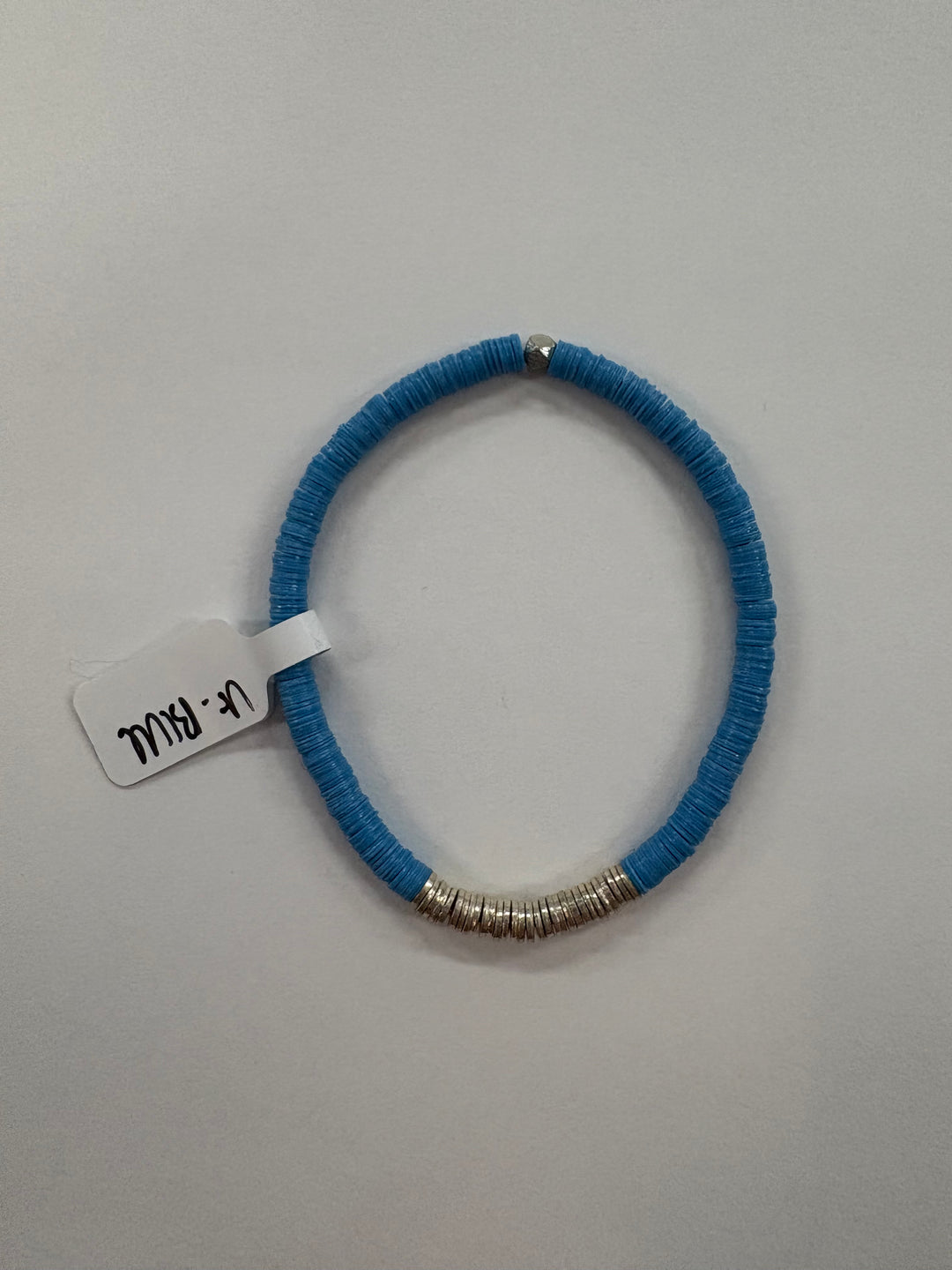 A blue flat bead bracelet with silver-plated accent beads and a small tag.