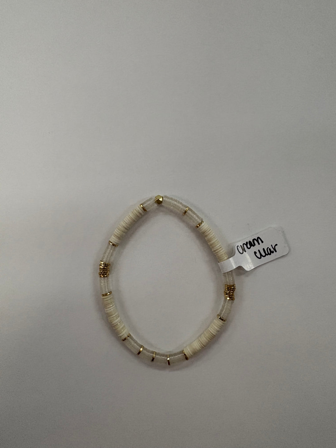 A cream and clear flat bead bracelet with gold accents.