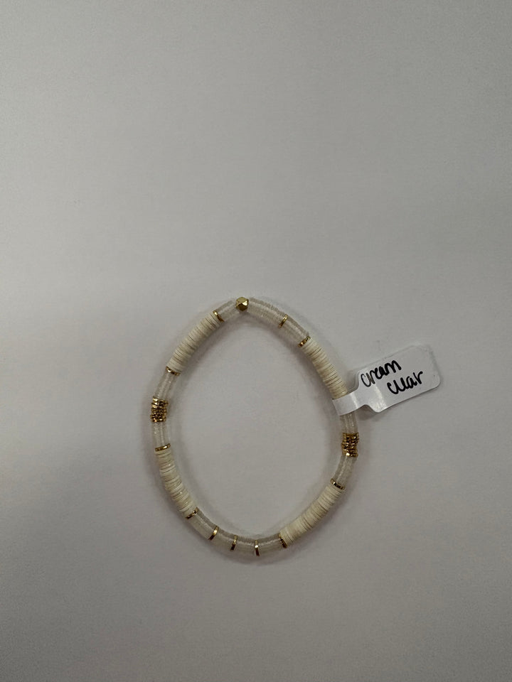 A cream and clear flat bead bracelet with gold accents.