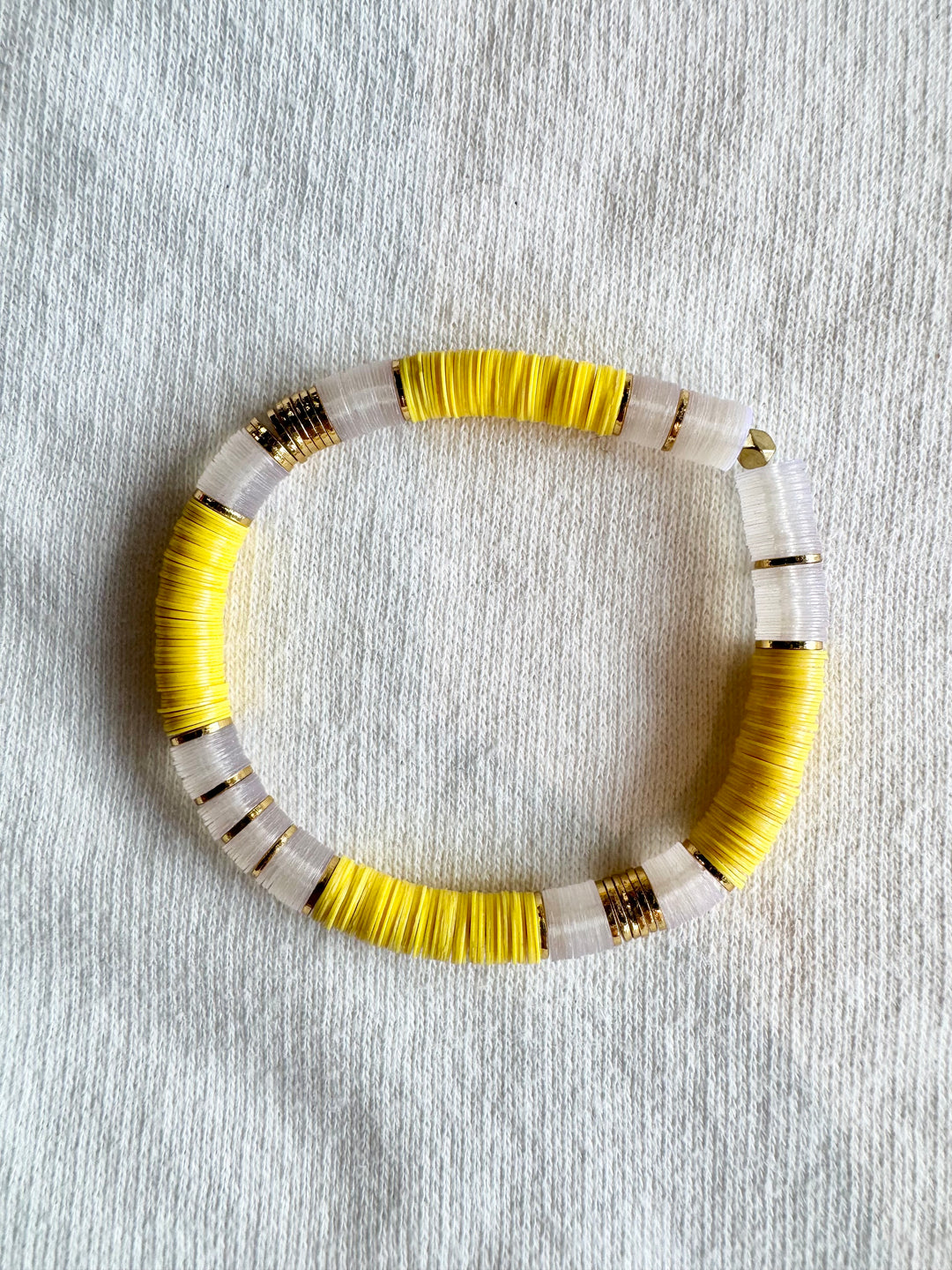 A large flat bead bracelet with alternating sections of yellow and clear beads, separated by gold rings.