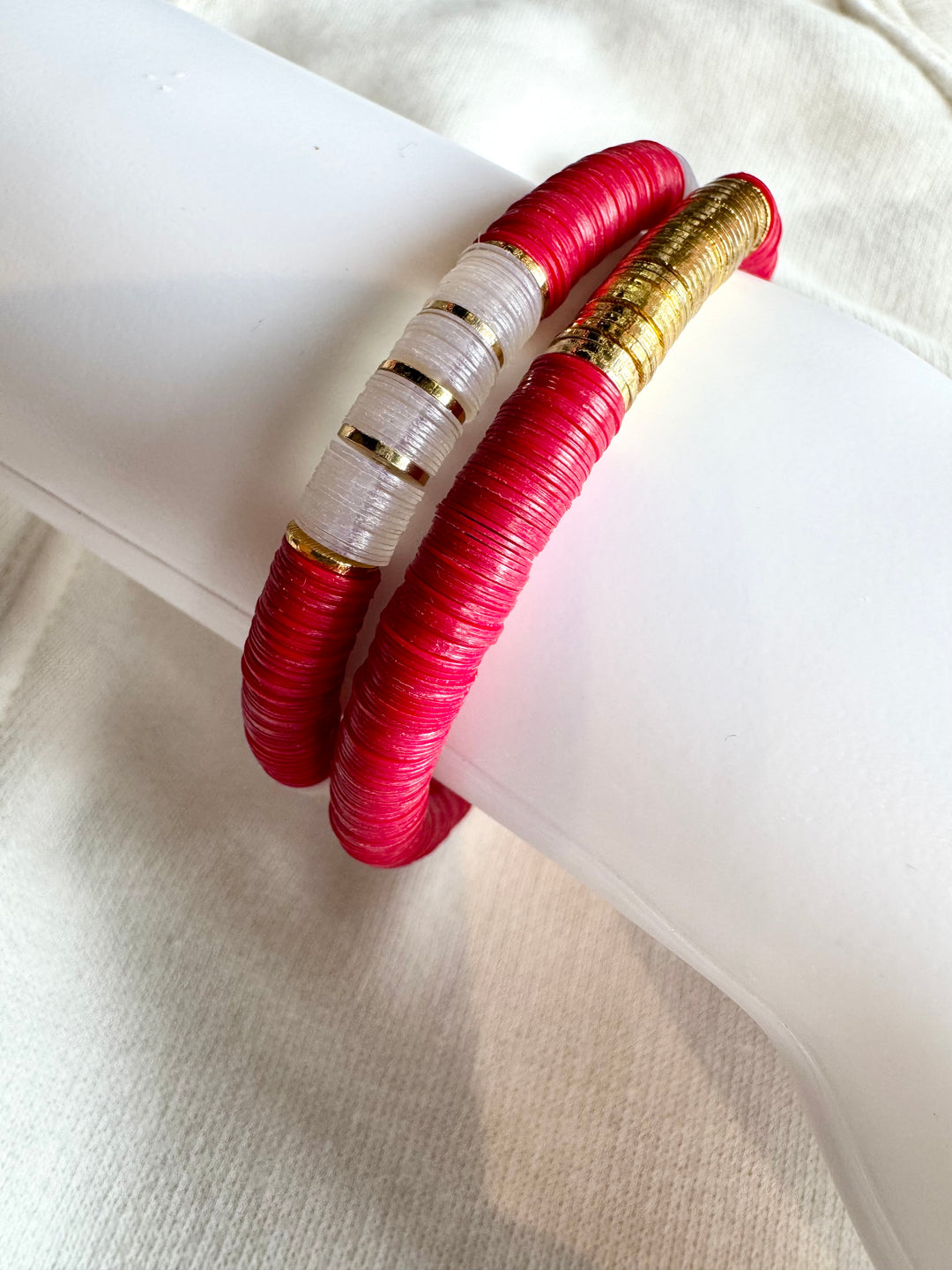 Two large flat bead bracelets, one white and gold, the other red and gold.