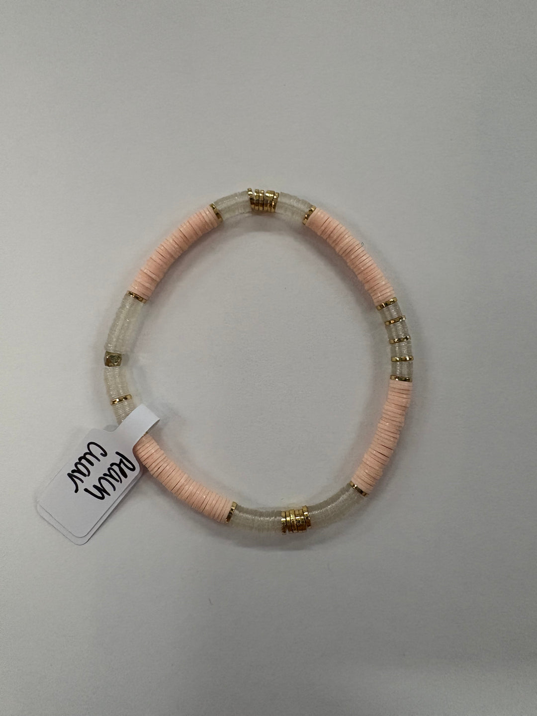Small flat bead bracelet with peach and clear vinyl beads and gold accents.
