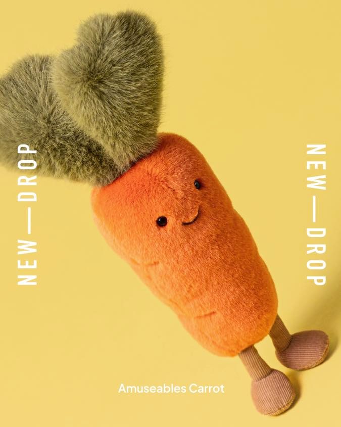 A plush carrot toy with green leafy hair and a smiling face.