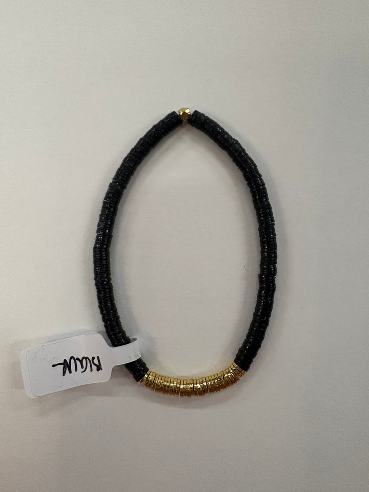 Small flat black bead bracelet with gold-plated beads and a tag that says "Blau."