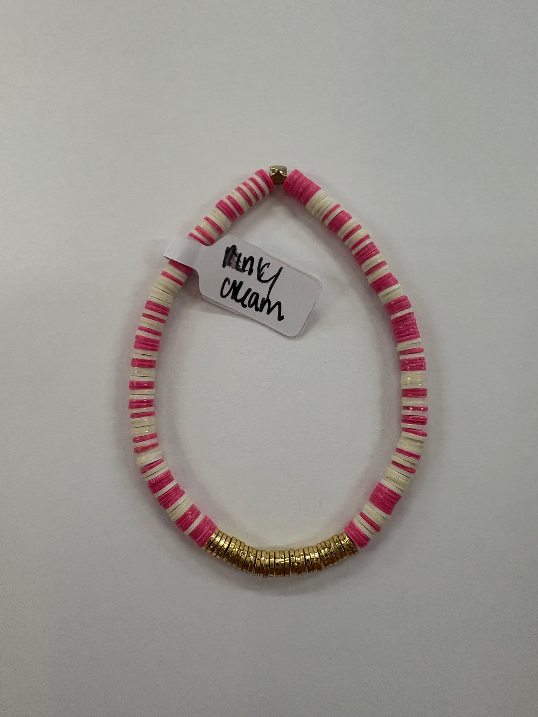 Small flat bead bracelet with alternating pink and cream vinyl beads and gold accents.