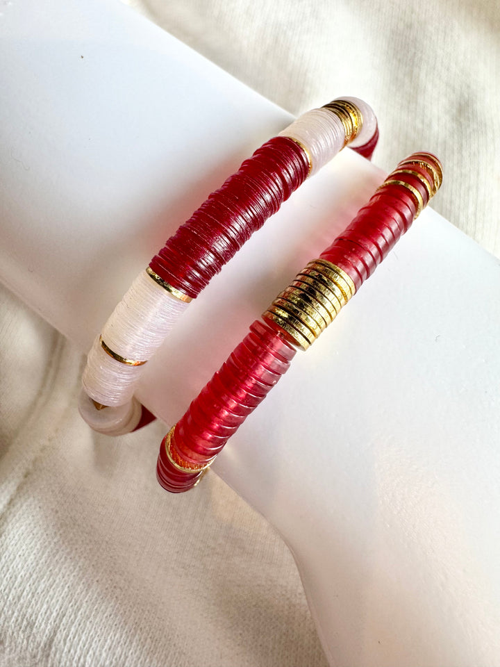 Two large flat bead bracelets, one red and white, the other red, with gold accents.