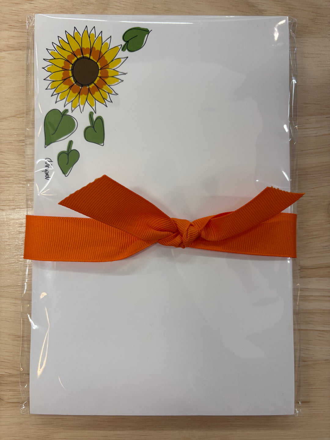 Sunflower notepad with an orange ribbon.