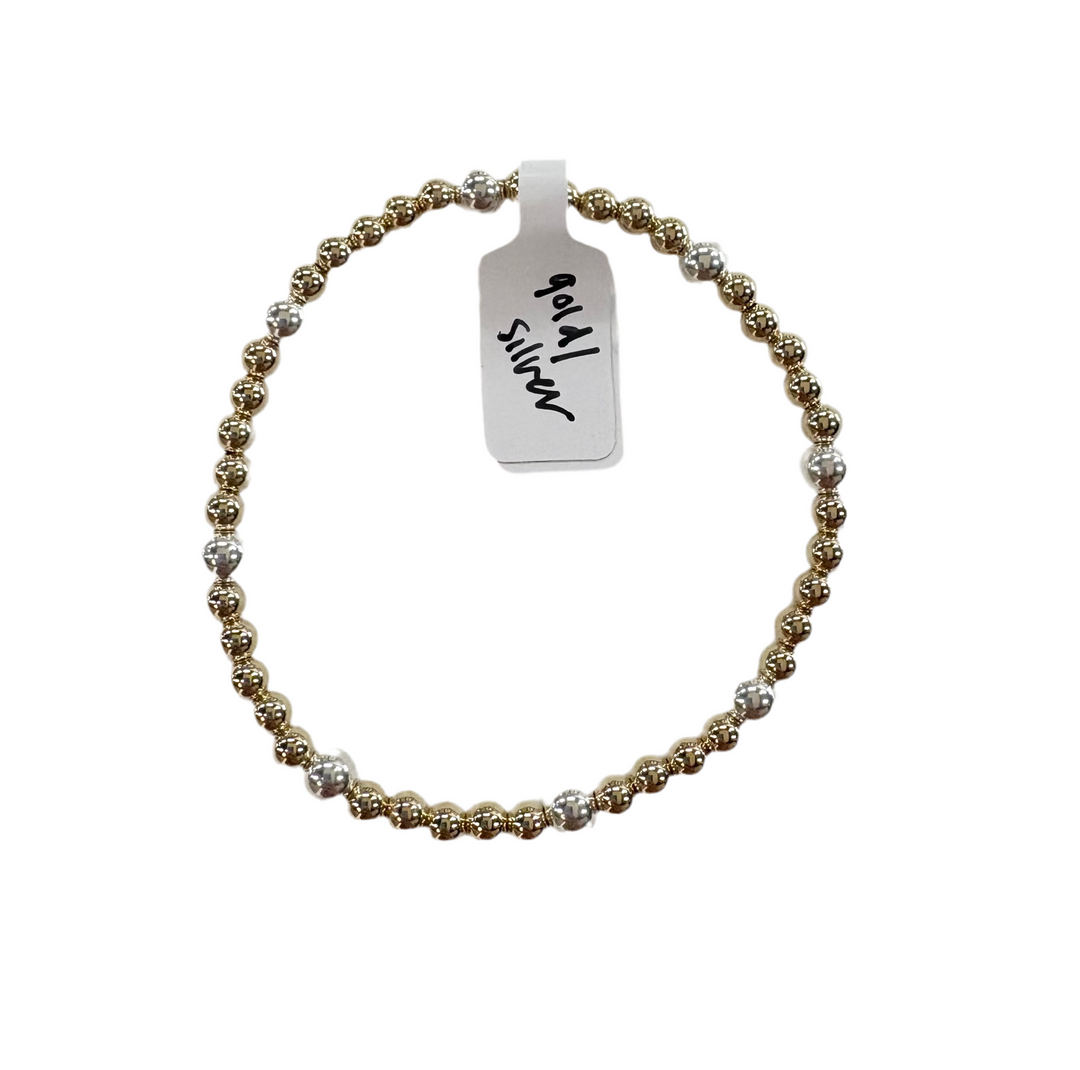 A beaded bracelet with alternating gold and silver beads, and a tag reading "gold / silver".