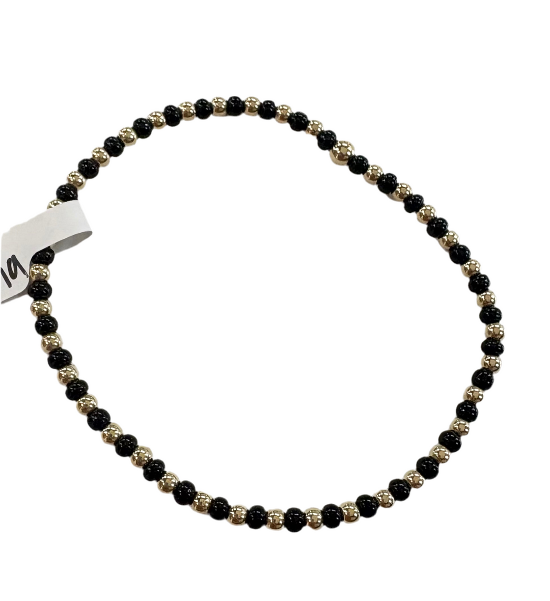 A black and gold beaded bracelet with a small white tag.