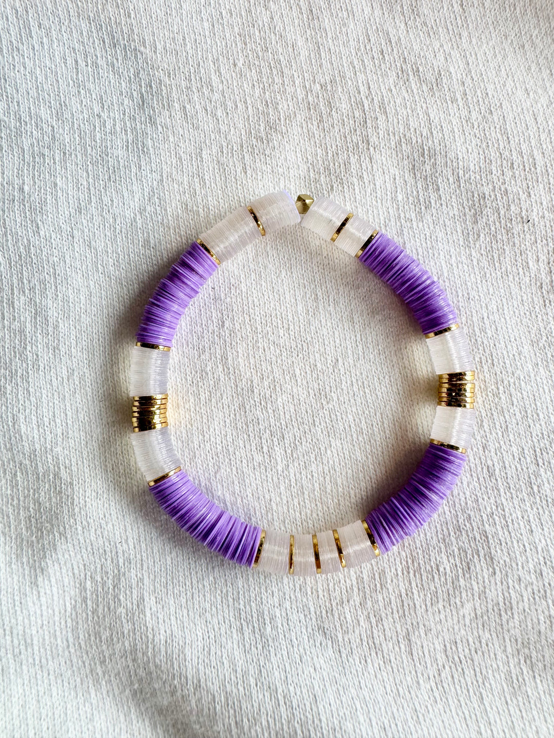 Large flat bead bracelet with purple and clear vinyl beads and gold spacers.