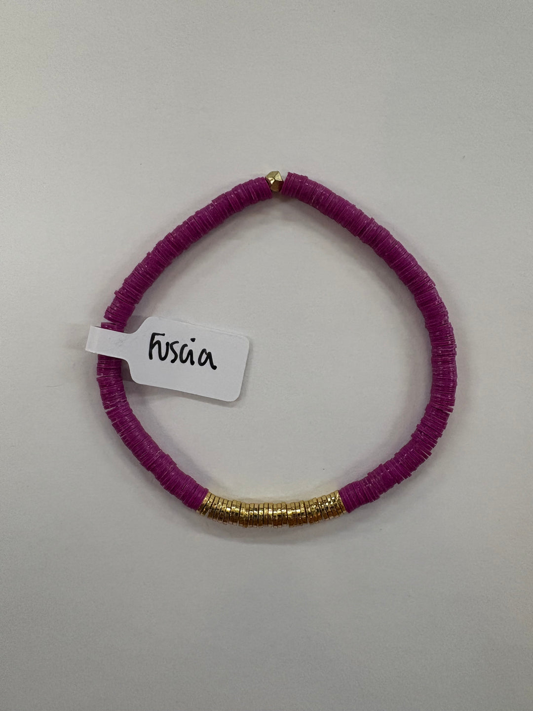 Small flat bead bracelet in fuscia with gold-plated accents.