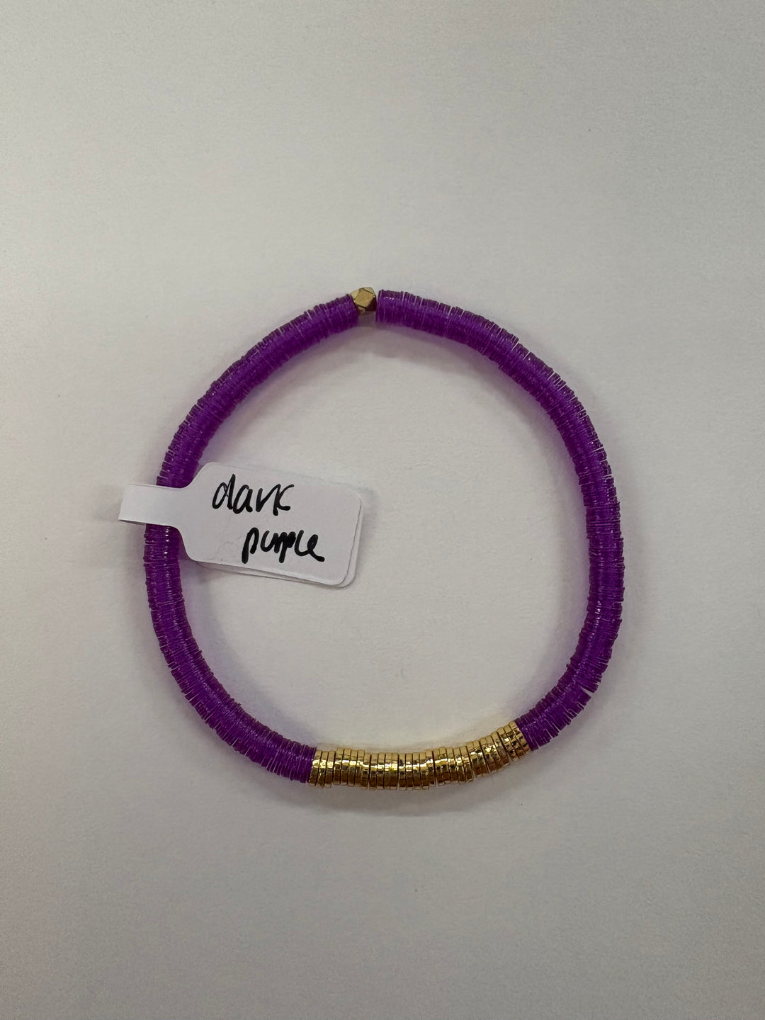 A dark purple flat bead bracelet with gold-plated beads and a tag reading "dark purple."