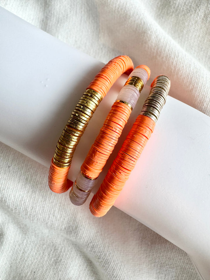 Three flat bead bracelets, one gold and two with gold and silver accents.