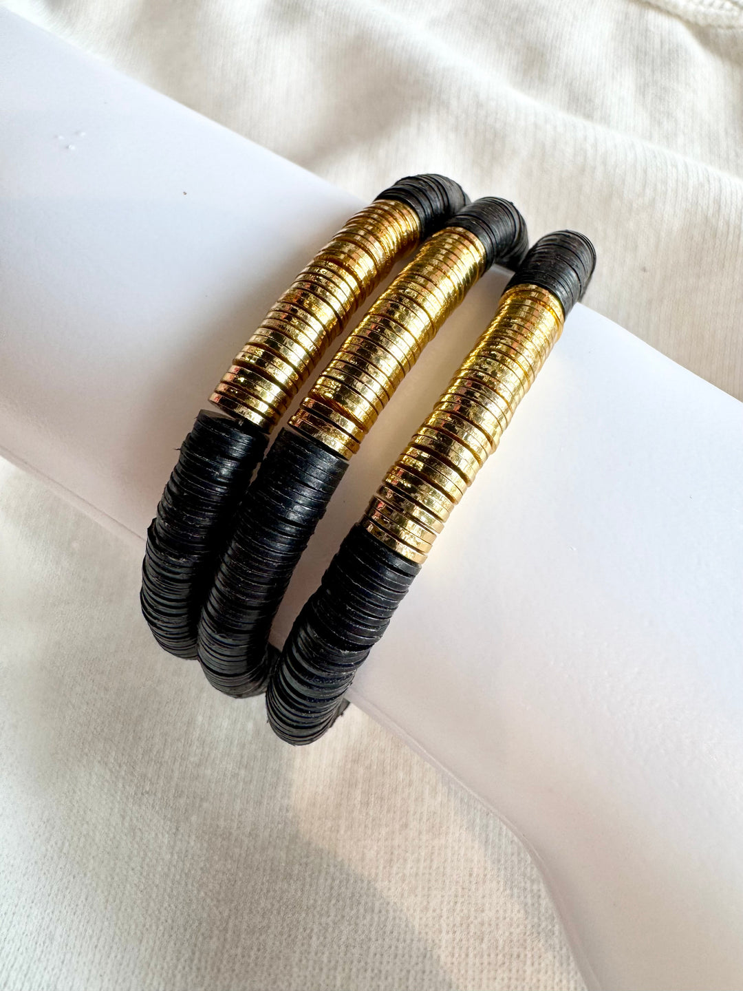 Three large flat bead bracelets with black and gold vinyl beads.