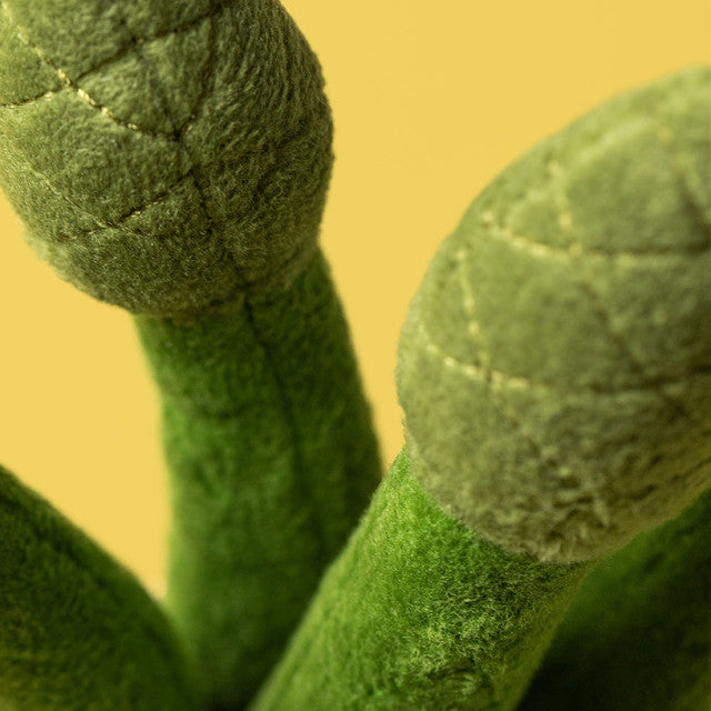 A close-up of a plush asparagus toy with green stalks and stitched details.