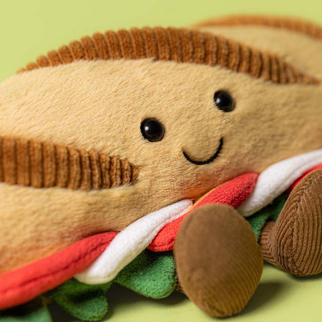 A plush toy baguette with a smiling face and visible layers of filling.