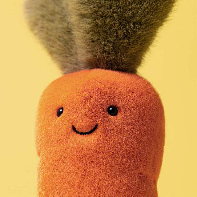 A plush carrot toy with a smiling face and green leafy top.