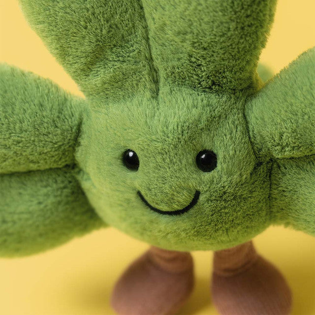 A green shamrock plush toy with a smiling face and brown feet.