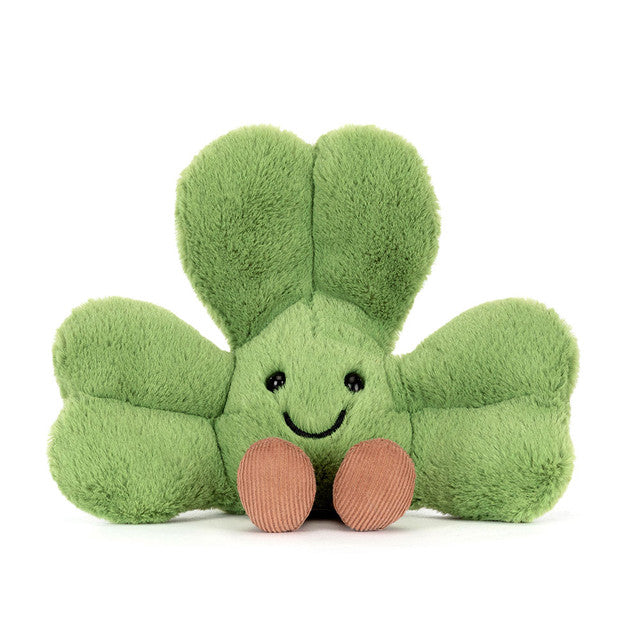 A green plush shamrock toy with a smiling face and brown feet.