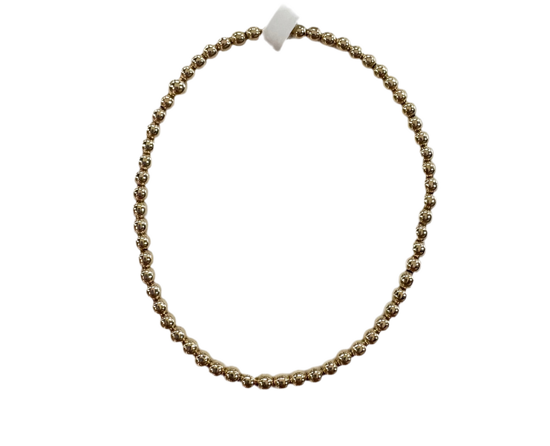 A gold-colored glass bead bracelet is displayed in a circular shape.