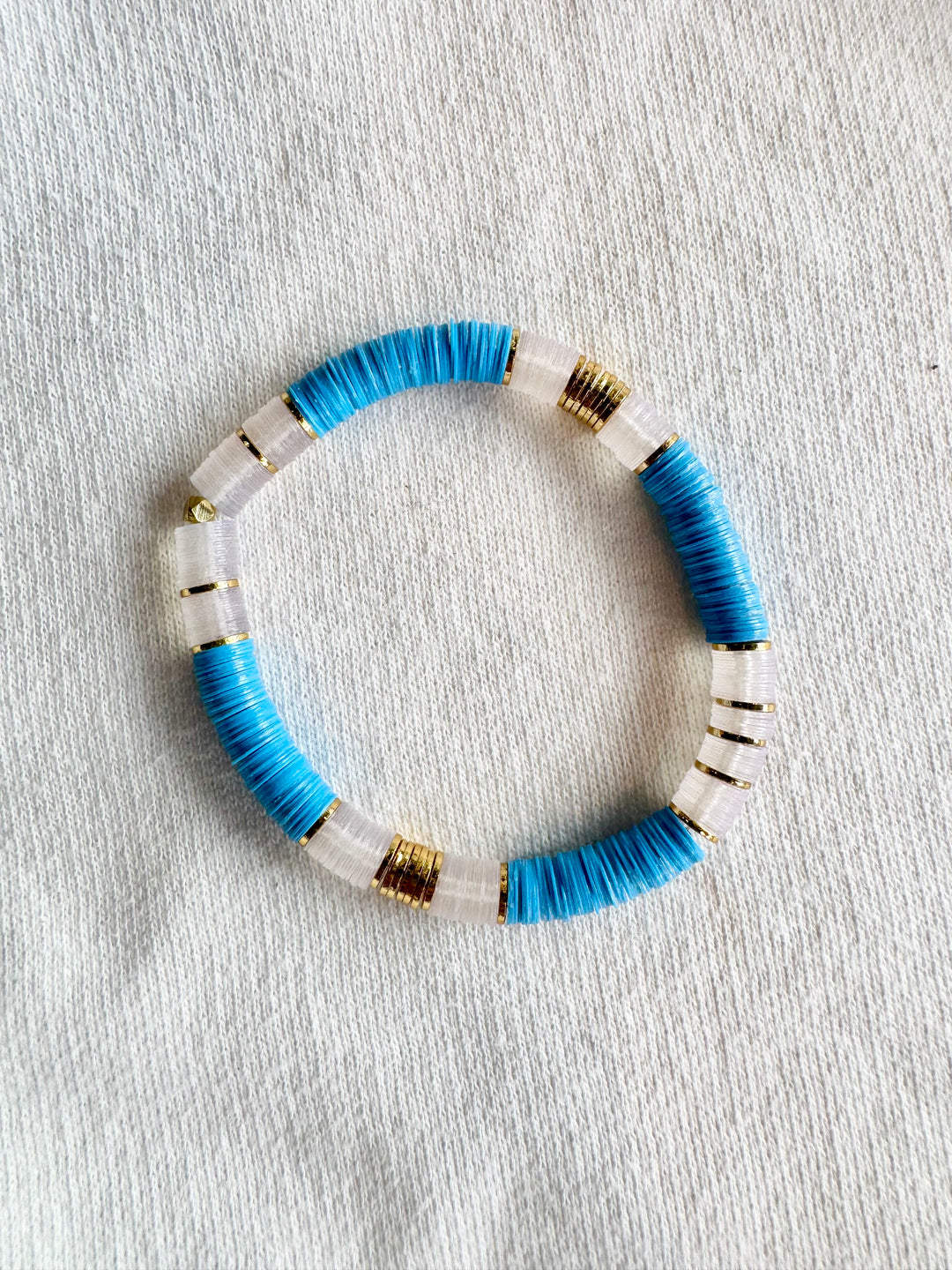 Large flat bead bracelet with blue and white vinyl beads and gold accents.