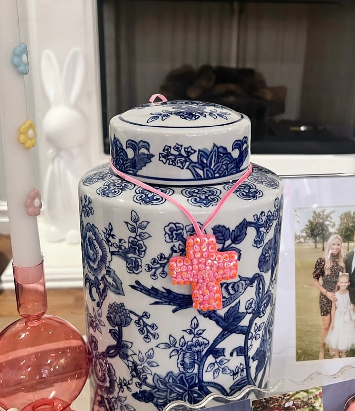 Mini Cross Hand Beaded Ornament, pink with orange accents, on a blue and white ginger jar.