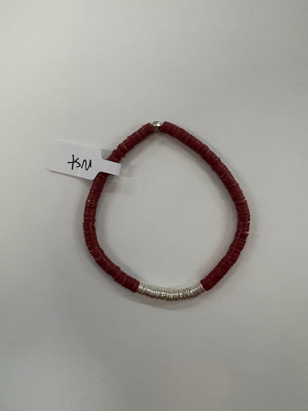 A small flat bead bracelet with red beads and a section of silver beads.