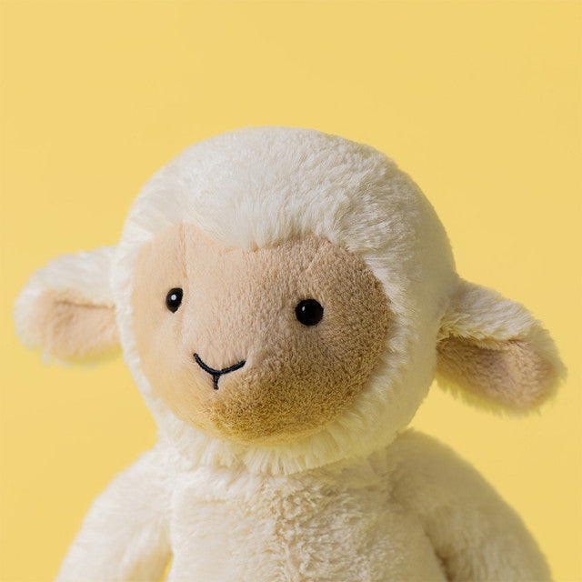 A fluffy white lamb stuffed animal with a tan face and black eyes and nose.