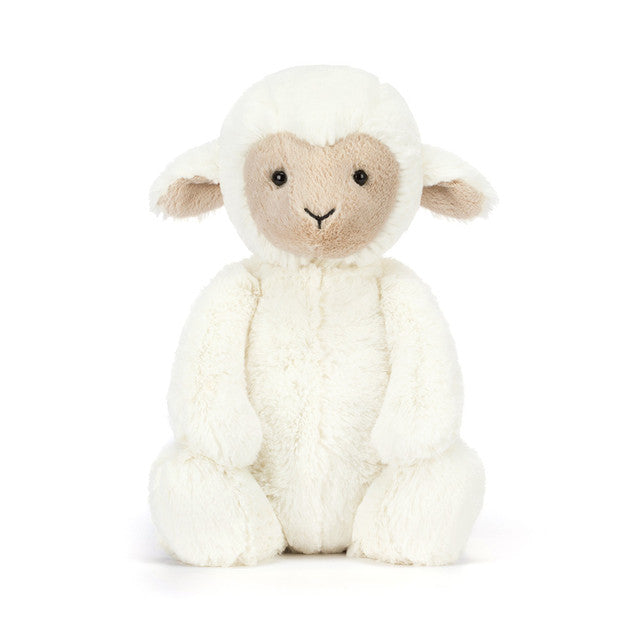 A fluffy white lamb stuffed animal sits facing forward.