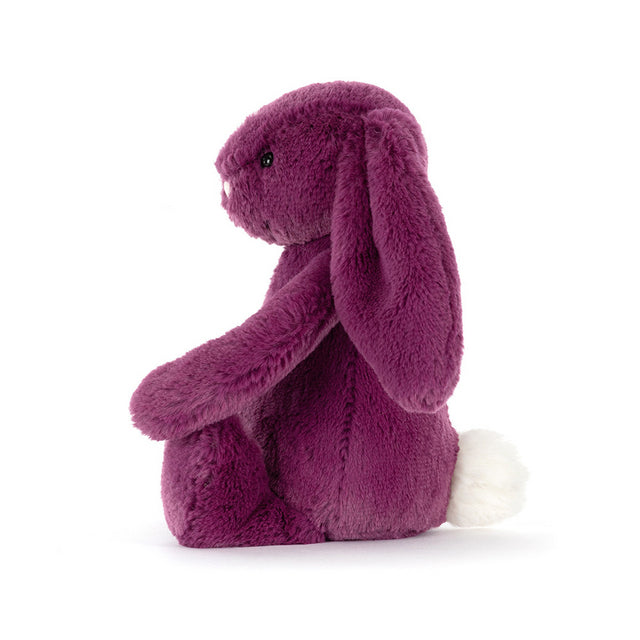 A purple plush bunny with a white fluffy tail sits facing left.