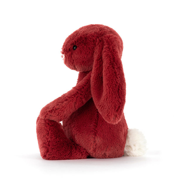 A redcurrant bunny plush toy with a white fluffy tail sits facing left.